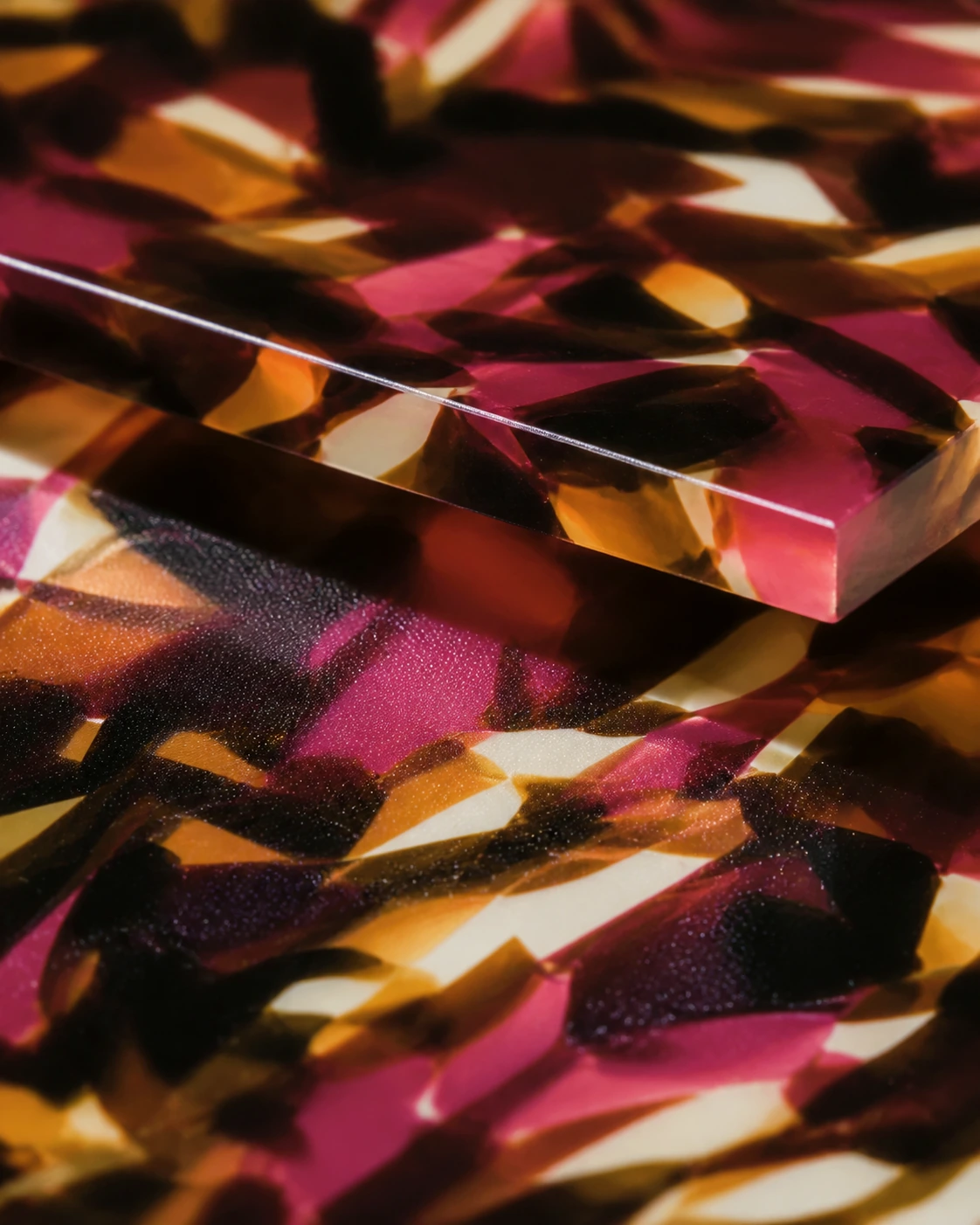 Macro of multicoloured acetate: rose, amber and ivory shards in translucent layers.